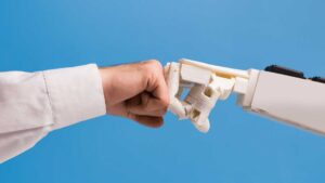 Main humaine sert le poing contre la main d'un robot sur un fond bleu