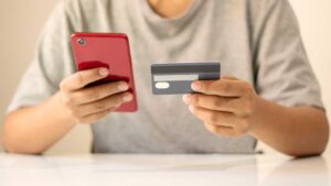 Homme qui passe une commande sur son téléphone avec sa carte bancaire à la main
