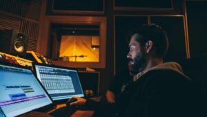 Homme devant son ordinateur et qui travaille sur un logiciel audio
